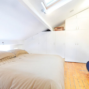 Kleines Modernes Schlafzimmer im Dachboden ohne Kamin mit weißer Wandfarbe und hellem Holzboden in Paris