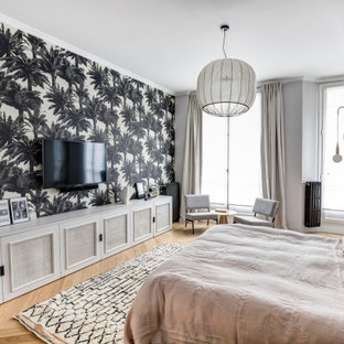 Exemple d'une chambre parentale tendance avec un mur multicolore, un sol en bois brun, un sol marron et du papier peint.