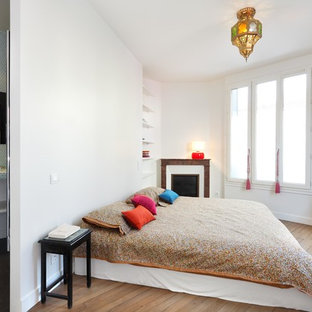 Réalisation d'une chambre bohème avec un mur blanc, un sol en bois brun et une cheminée d'angle.
