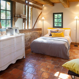 Diseño de habitación de invitados campestre, de tamaño medio, con paredes blancas y suelo de baldosas de terracota