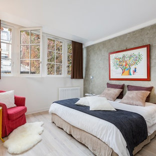 Inspiration pour une chambre d'amis bohème avec un mur blanc, un sol en bois clair et un sol beige.