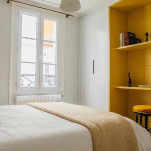 Cette image montre une petit chambre d'amis design avec un mur gris, un sol en bois brun et un sol beige.