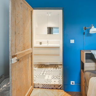 Foto de dormitorio nórdico con paredes azules, suelo de madera en tonos medios, chimenea de doble cara y suelo marrón