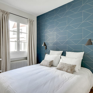 Idée de décoration pour une chambre d'amis nordique avec un mur bleu, un sol en bois clair et un sol beige.