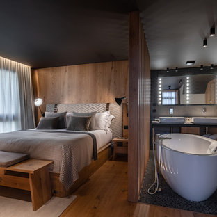Idée de décoration pour une chambre parentale chalet avec un mur marron, un sol en bois brun et un sol marron.