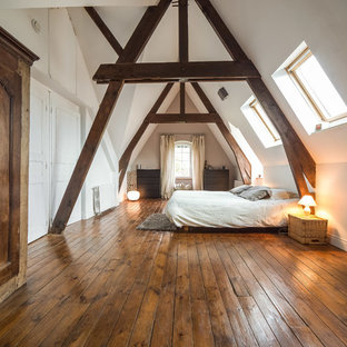 Inspiration pour une chambre rustique avec un mur blanc et un sol en bois brun.