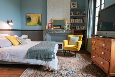 Idée de décoration pour une chambre parentale champêtre avec un mur bleu, parquet foncé, une cheminée standard, un manteau de cheminée en pierre et un sol marron.