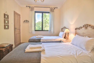 Ejemplo de habitación de invitados campestre de tamaño medio con paredes beige, suelo de travertino y suelo beige