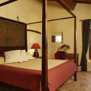 Ejemplo de habitación de invitados tradicional, de tamaño medio, con paredes amarillas y suelo de baldosas de terracota