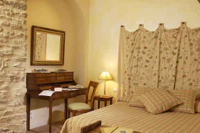 Cette image montre une chambre d'amis traditionnelle de taille moyenne avec un mur beige et tomettes au sol.