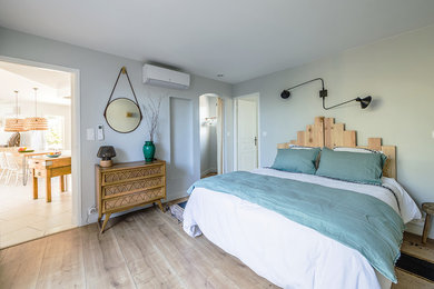 Imagen de dormitorio principal nórdico de tamaño medio sin chimenea con paredes grises y suelo de madera clara