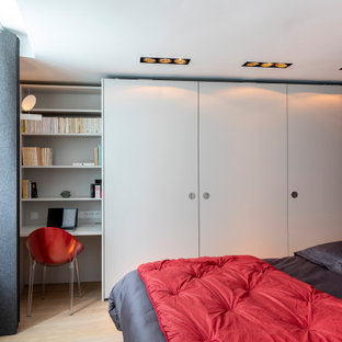 Idée de décoration pour une chambre parentale design de taille moyenne avec un mur blanc, un sol en bois clair et un sol beige.