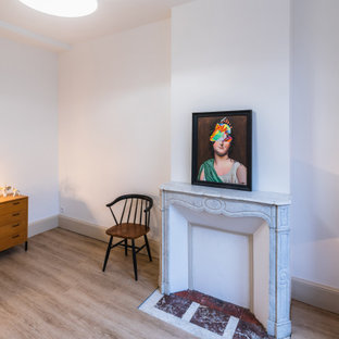 Diseño de dormitorio principal, retro, de tamaño medio, con paredes blancas, suelo de linóleo, chimenea tradicional, marco de chimenea de piedra y suelo marrón