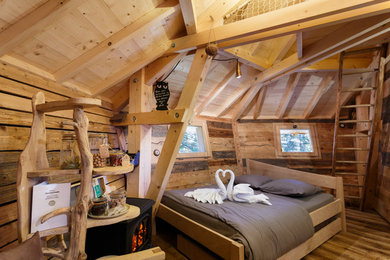 Modelo de dormitorio principal campestre de tamaño medio con paredes marrones, suelo de madera oscura, estufa de leña y suelo marrón