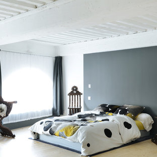 Inspiration pour une chambre bohème avec un mur gris, un sol en bois clair et un sol beige.