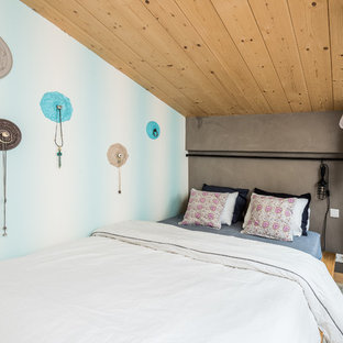 Cette photo montre une chambre mansardée ou avec mezzanine tendance de taille moyenne avec un mur gris, béton au sol et aucune cheminée.