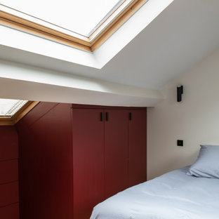 Diseño de dormitorio urbano, de tamaño medio, con paredes rojas y suelo de madera clara