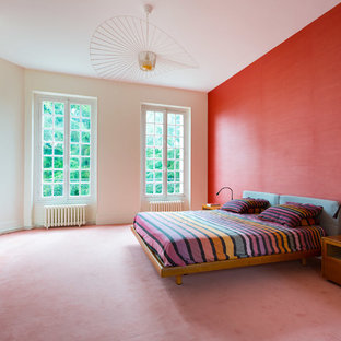 Modelo de dormitorio principal, contemporáneo, con paredes rojas, moqueta, suelo rosa, chimeneas suspendidas y marco de chimenea de metal