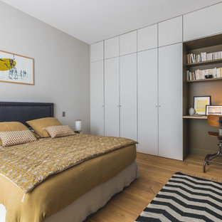 Inspiration pour une chambre design avec un mur blanc, un sol en bois brun et un sol marron.