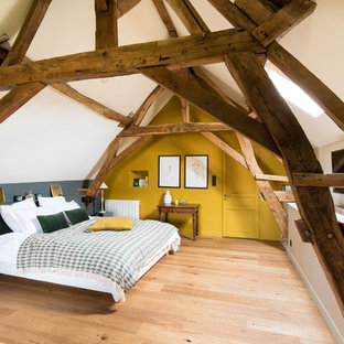 Cette image montre une chambre rustique avec un mur jaune, un sol en bois clair et un sol beige.