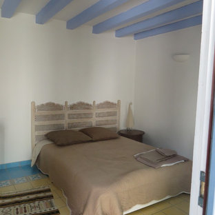 Modelo de dormitorio principal, de estilo de casa de campo, de tamaño medio, con paredes blancas, suelo de baldosas de cerámica y suelo amarillo