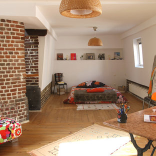 Cette photo montre une chambre parentale éclectique de taille moyenne avec un mur blanc, un sol en bois brun et un sol marron.