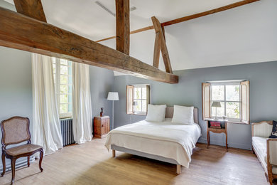 Exemple d'une grande chambre d'amis nature avec un mur gris, un sol en bois brun et aucune cheminée.