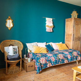 Ejemplo de habitación de invitados campestre, grande, con paredes negras y suelo de madera clara