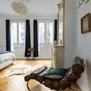 Cette photo montre une grand chambre parentale scandinave avec un mur blanc, un sol en bois clair, aucune cheminée et un sol marron.