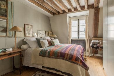 This is an example of a mediterranean grey and brown bedroom in Paris with grey walls, medium hardwood flooring and brown floors.