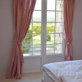 Modelo de dormitorio principal, campestre, de tamaño medio, con paredes blancas, suelo de travertino y suelo beige