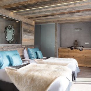 Idée de décoration pour une chambre d'amis chalet avec un mur marron, un sol en bois clair et un sol marron.