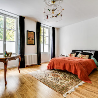 Idée de décoration pour une chambre design avec un mur blanc, un sol en bois brun et un sol marron.