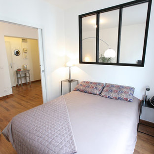 Ejemplo de dormitorio principal, actual, pequeño, con paredes blancas, suelo de madera oscura y chimenea lineal