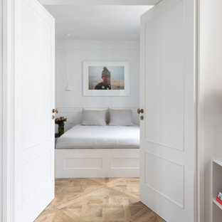 Aménagement d'une chambre contemporaine avec un mur blanc, un sol en bois brun, un sol marron et du lambris.