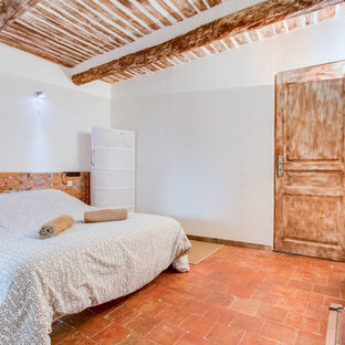 Ejemplo de habitación de invitados de estilo de casa de campo, grande, sin chimenea, con paredes blancas y suelo de baldosas de terracota