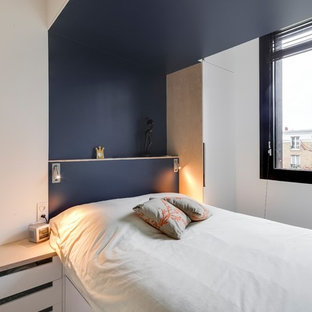 Imagen de dormitorio principal, actual, pequeño, sin chimenea, con paredes azules, suelo de contrachapado y suelo marrón