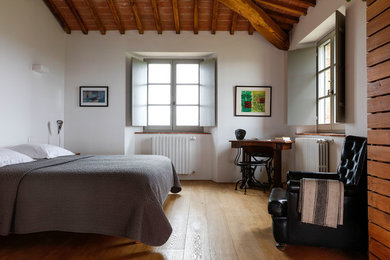 Idée de décoration pour une chambre méditerranéenne avec un mur blanc, un sol en bois brun et un sol marron.