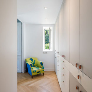 Diseño de dormitorio principal, actual, pequeño, con paredes blancas, suelo de madera clara, chimenea de esquina, marco de chimenea de hormigón y suelo beige