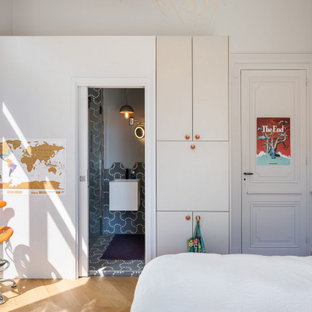 Modelo de dormitorio actual, pequeño, con paredes blancas, suelo de madera clara, chimenea de esquina, marco de chimenea de hormigón y suelo beige