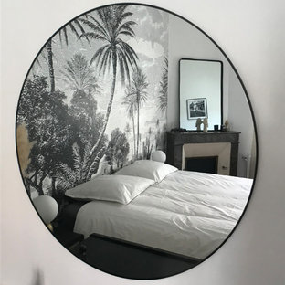 Diseño de dormitorio principal y papel pintado, exótico, de tamaño medio, papel pintado, con paredes blancas, suelo de madera en tonos medios, chimenea de esquina, marco de chimenea de piedra, suelo marrón y papel pintado