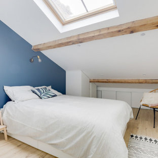 Cette image montre une chambre nordique de taille moyenne avec un mur bleu, sol en stratifié, un sol beige, un plafond en poutres apparentes et un plafond voûté.