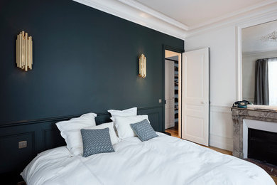 Idée de décoration pour une chambre parentale design de taille moyenne avec une cheminée standard, un manteau de cheminée en pierre, un mur bleu, parquet foncé et un sol marron.