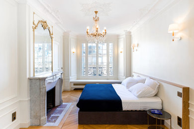 Ejemplo de dormitorio blanco y madera tradicional con paredes blancas, suelo de madera clara, todas las chimeneas y suelo beige