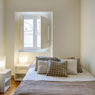Réalisation d'une petit chambre parentale design avec un mur blanc et un sol en bois brun.