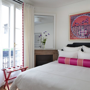 Cette photo montre une chambre d'amis chic avec un mur blanc, un sol en bois brun et une cheminée d'angle.