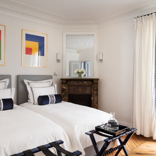Idées déco pour une chambre d'amis classique avec un mur blanc, un sol en bois brun et une cheminée d'angle.
