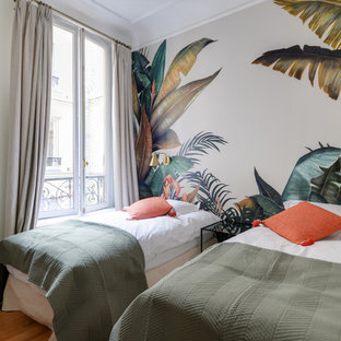 Aménagement d'une chambre d'amis contemporaine avec un mur blanc, un sol en bois brun et un sol marron.