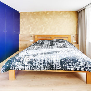 Imagen de dormitorio principal, minimalista, de tamaño medio, sin chimenea, con paredes azules, suelo laminado y suelo violeta