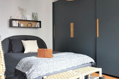 Cette image montre une chambre design avec un mur blanc, un sol en bois brun et un sol marron.